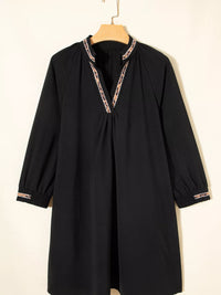 Black dress with lace trim on a hanger against a white background