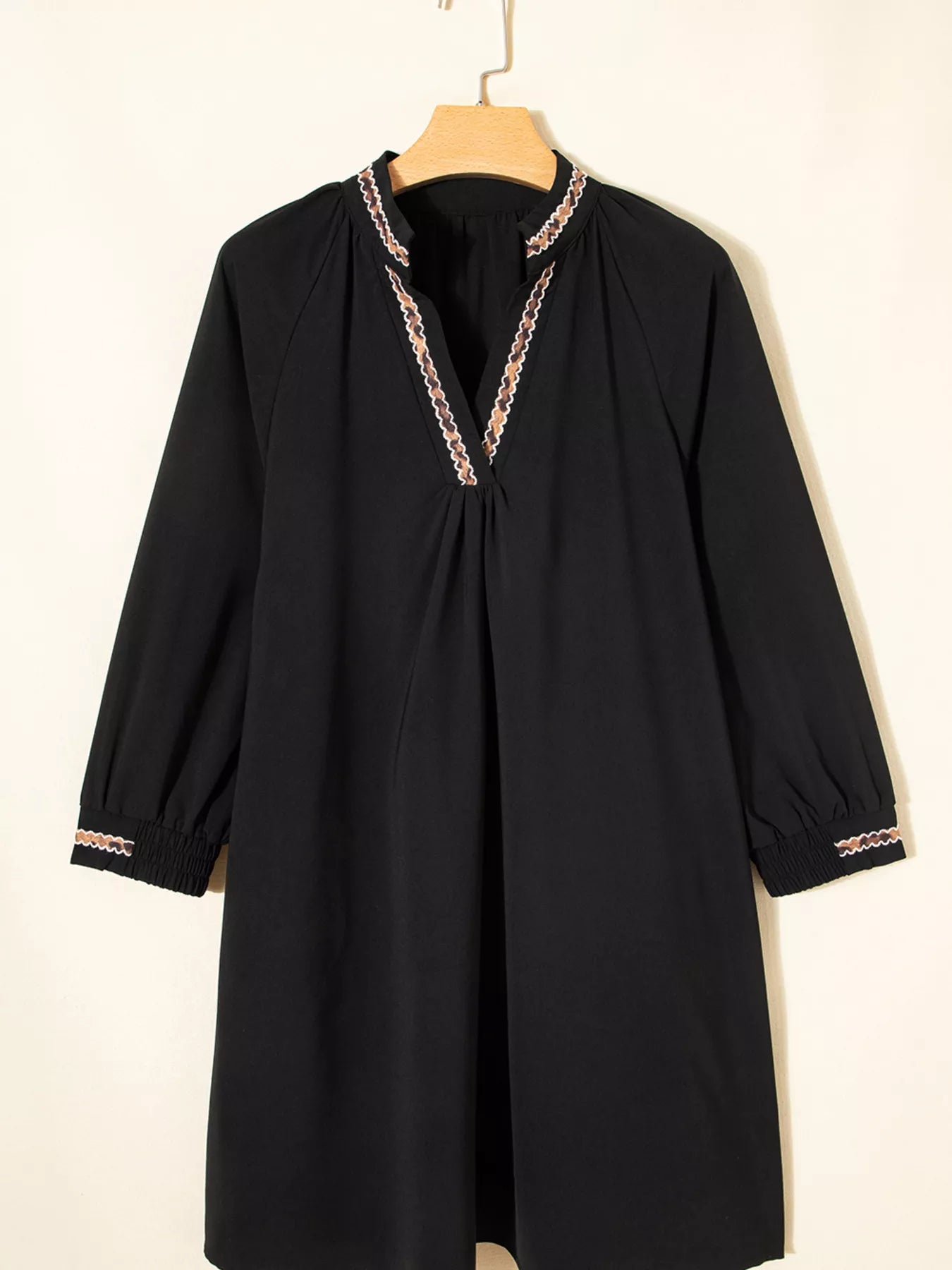 Black dress with lace trim on a hanger against a white background