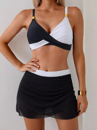 Woman wearing a black and white bikini with a matching skirt against a neutral background