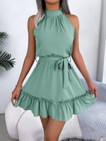 Green dress with ruffled hem worn by a person, sitting on a white couch.