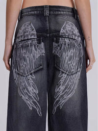 Black jeans with wing designs on the back pockets against a white background
