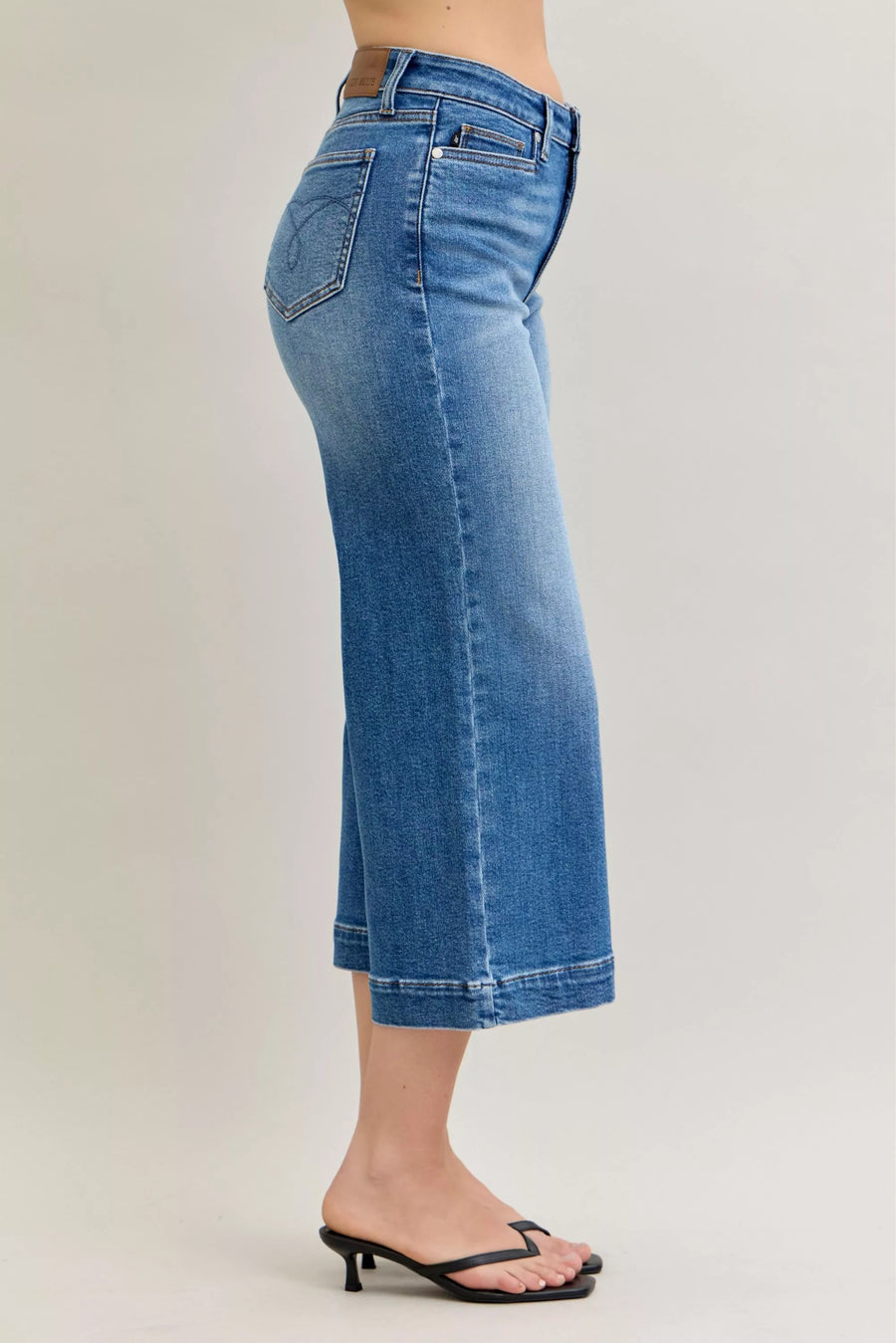 Blue jeans worn by a person on a plain background