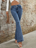 Person wearing blue flared jeans against a stone wall.