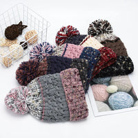 Collection of knitted hats with pom-poms and yarn balls on a white background