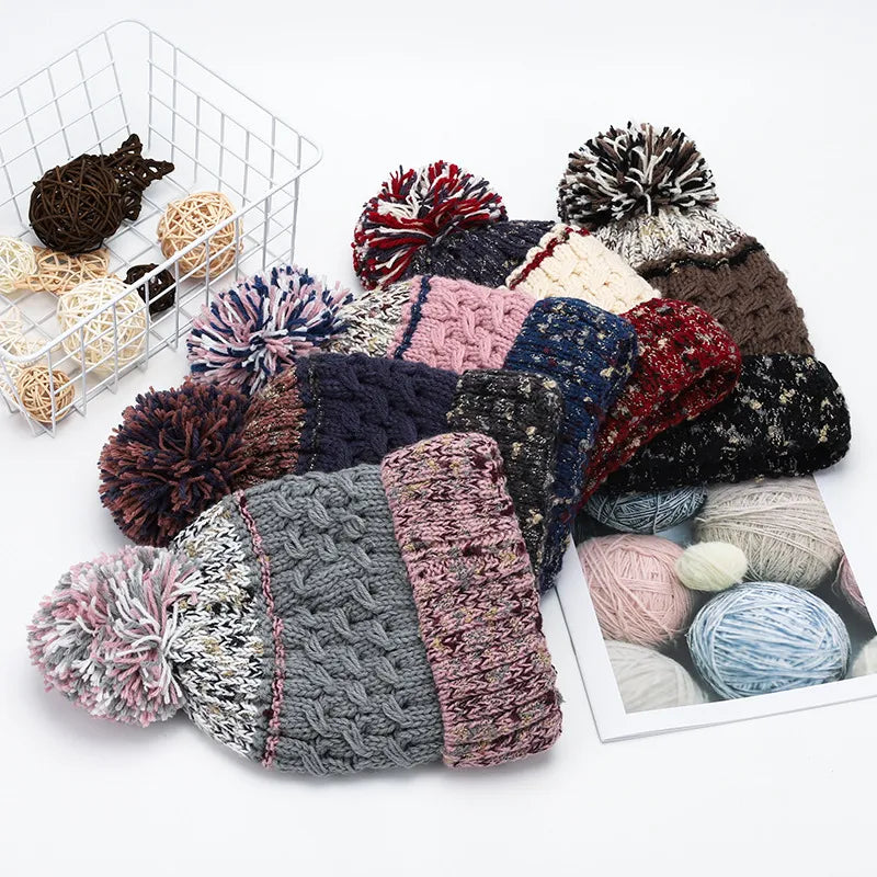 Collection of knitted hats with pom-poms and yarn balls on a white background