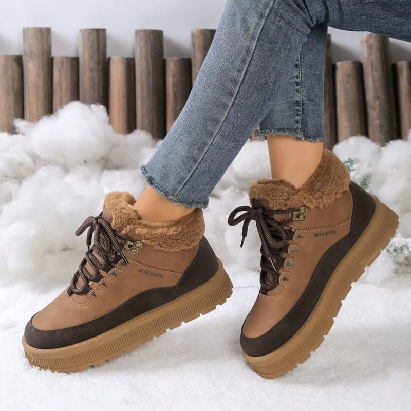 Brown winter boots with fur lining worn by a person in a snowy setting.