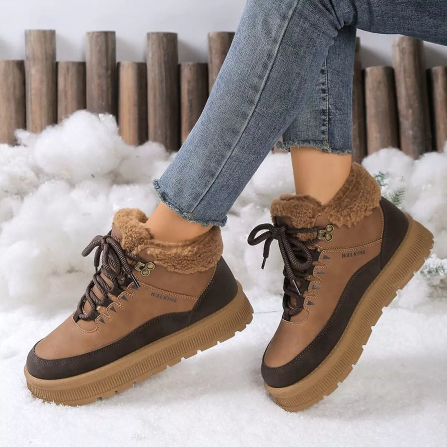 Brown winter boots with fur lining worn by a person in a snowy setting.