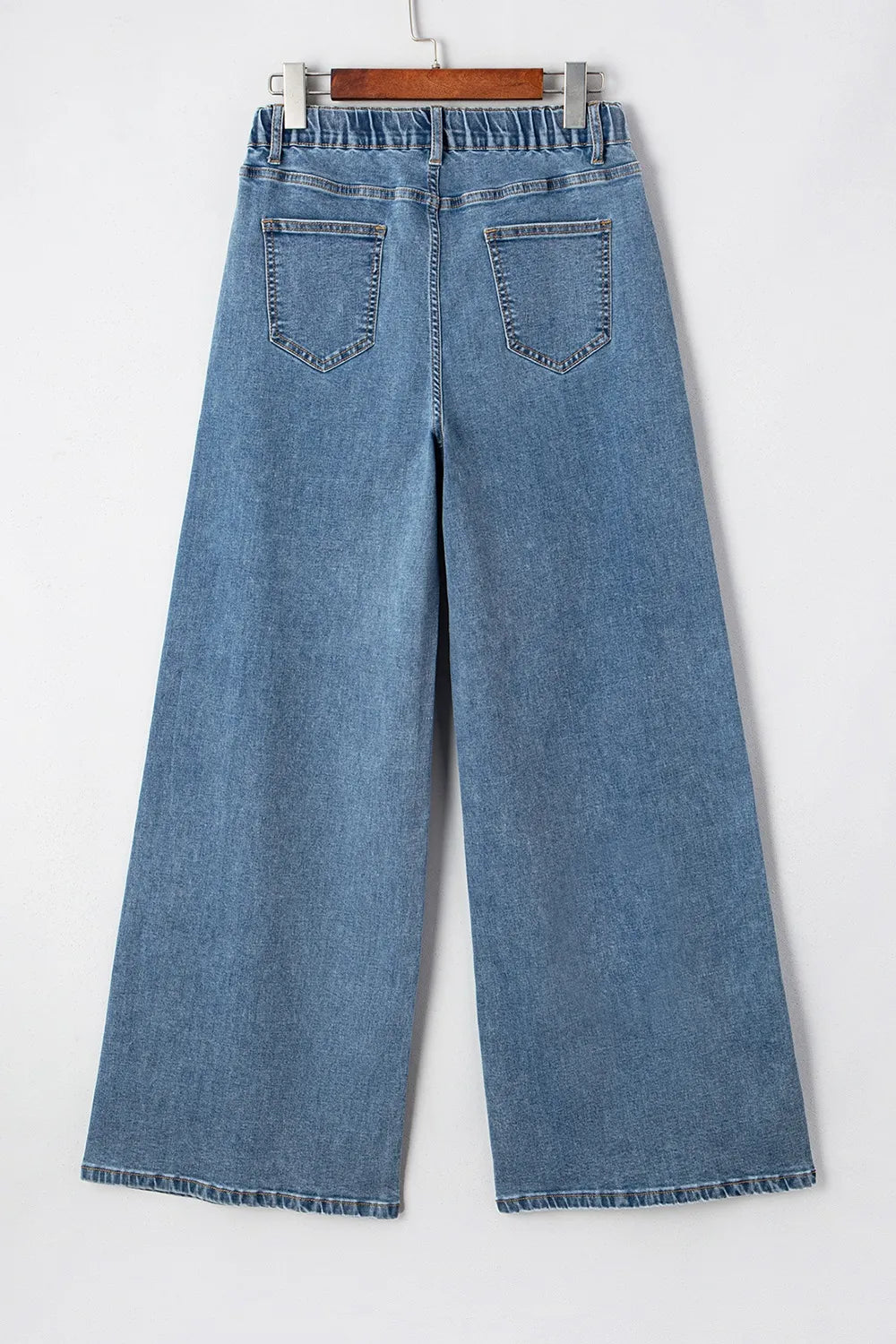 Blue jeans on a hanger against a white background