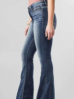 Blue flared jeans worn by a person on a gray background