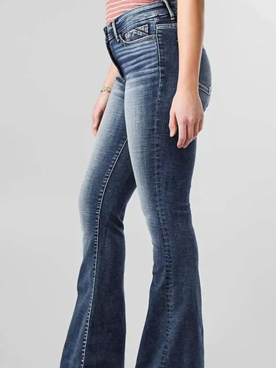 Blue flared jeans worn by a person on a gray background