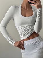 Person wearing a fitted white long-sleeve top against a neutral background