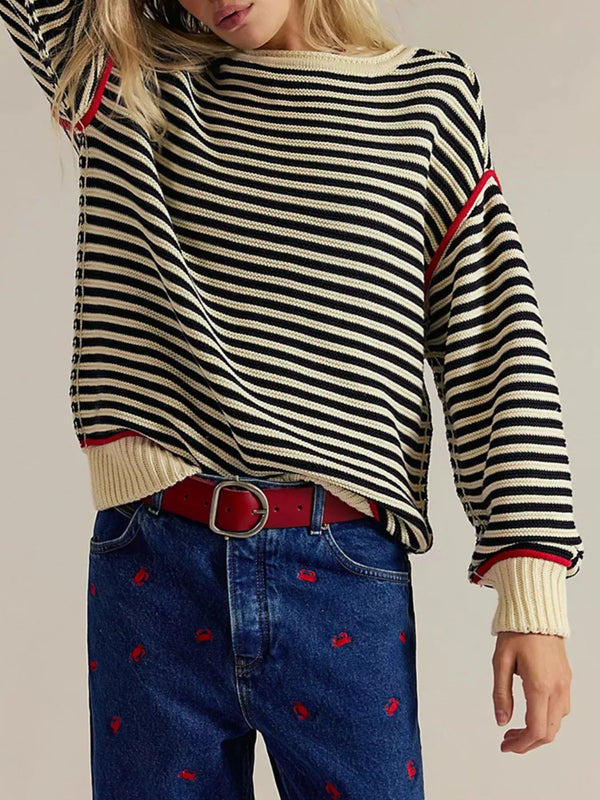 Person wearing a black and white striped sweater with red accents and blue jeans with red patterns.