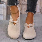 Beige loafers with rope details worn by a person on a concrete floor.