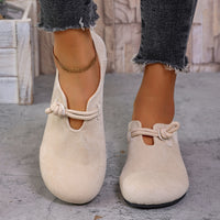 Beige loafers with rope details worn by a person on a concrete floor.