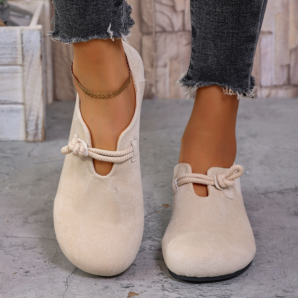 Beige loafers with rope details worn by a person on a concrete floor.