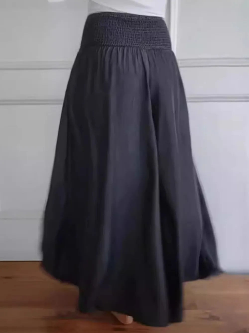 Long dark gray skirt with a textured waistband on a neutral background