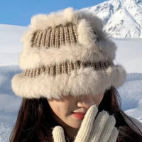 Person wearing a fluffy winter hat and gloves in a snowy landscape