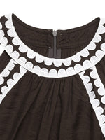 Black dress with white scalloped trim on a white background