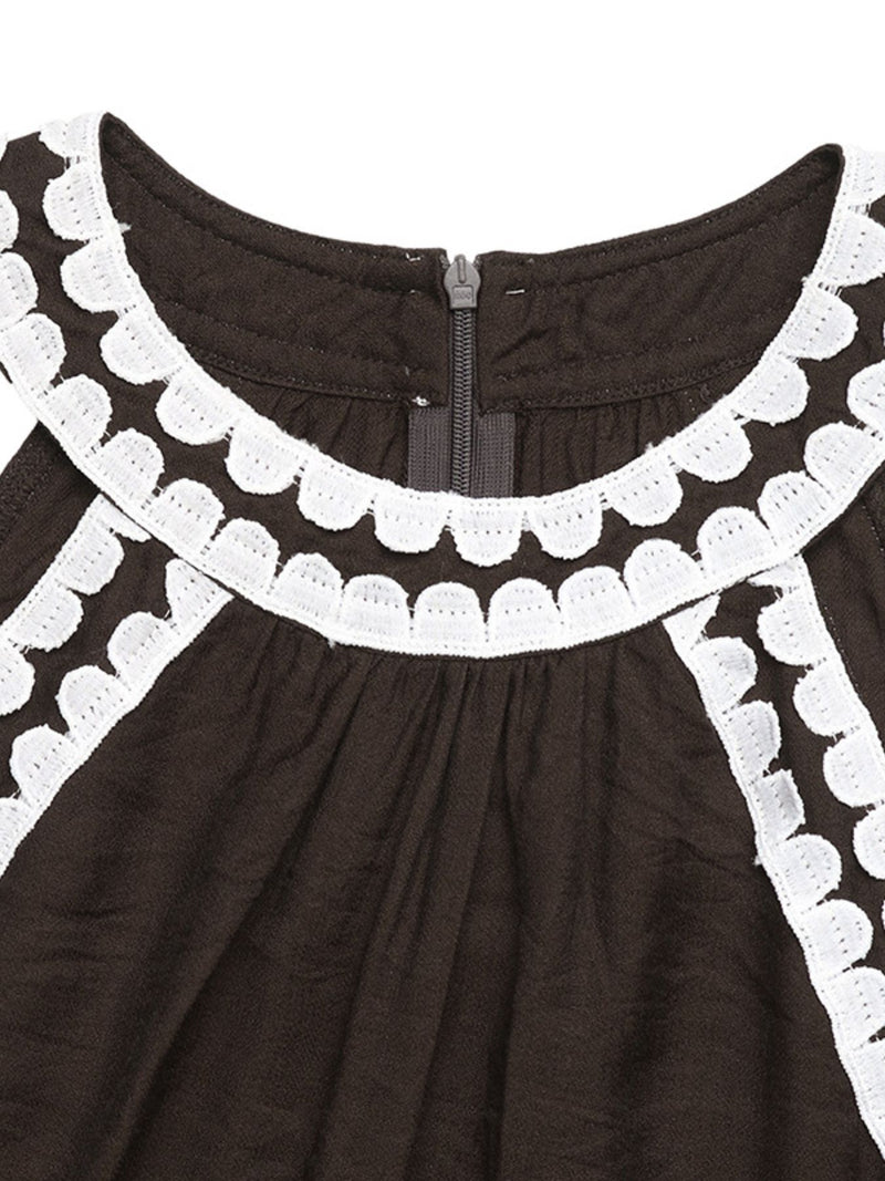 Black dress with white scalloped trim on a white background