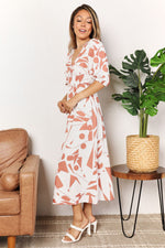 Woman in a floral dress standing in a living room with a plant and couch.