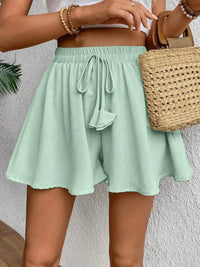 Person wearing light green shorts with a woven bag against a neutral background