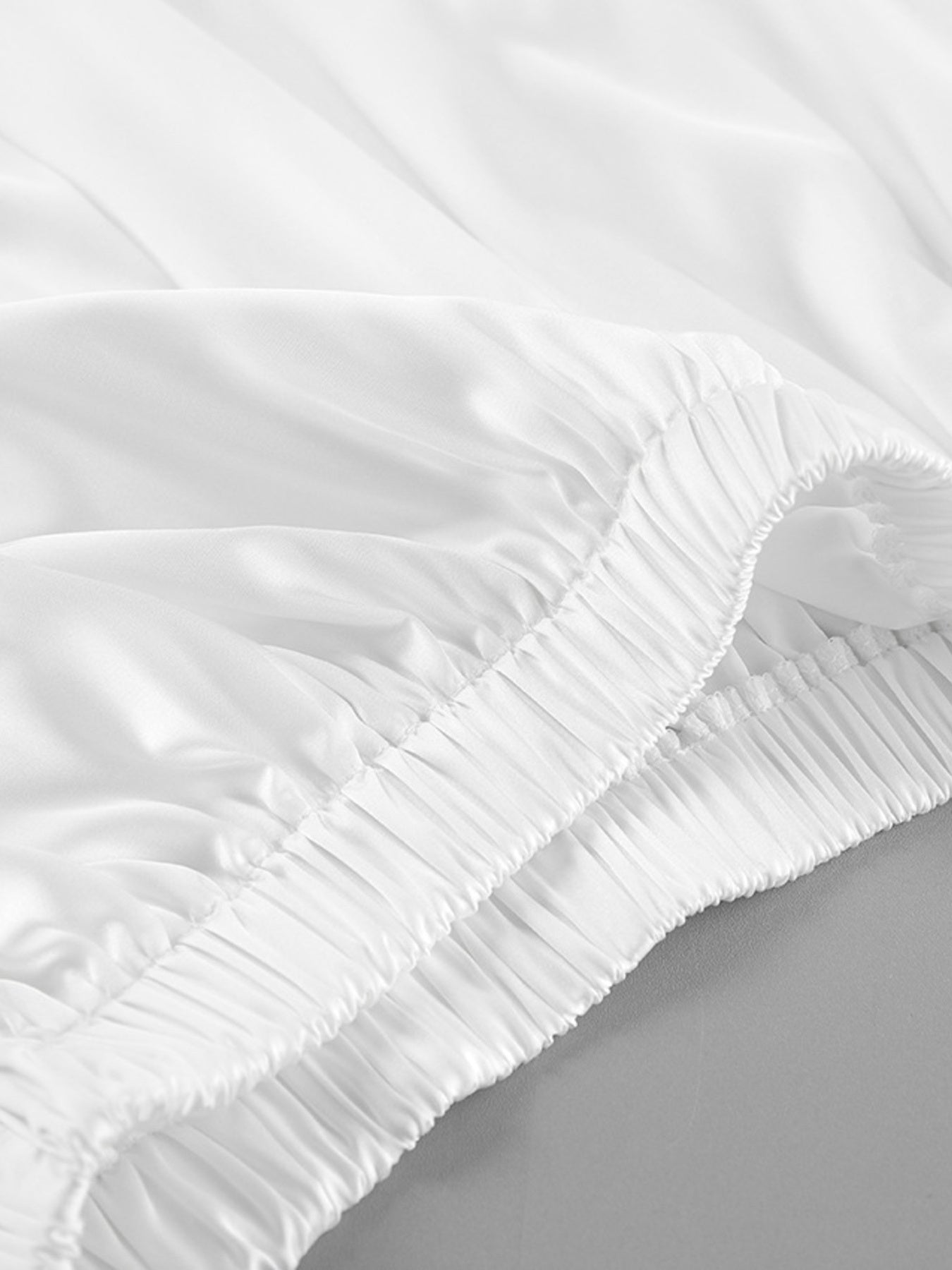 Close-up of a white fitted sheet on a bed