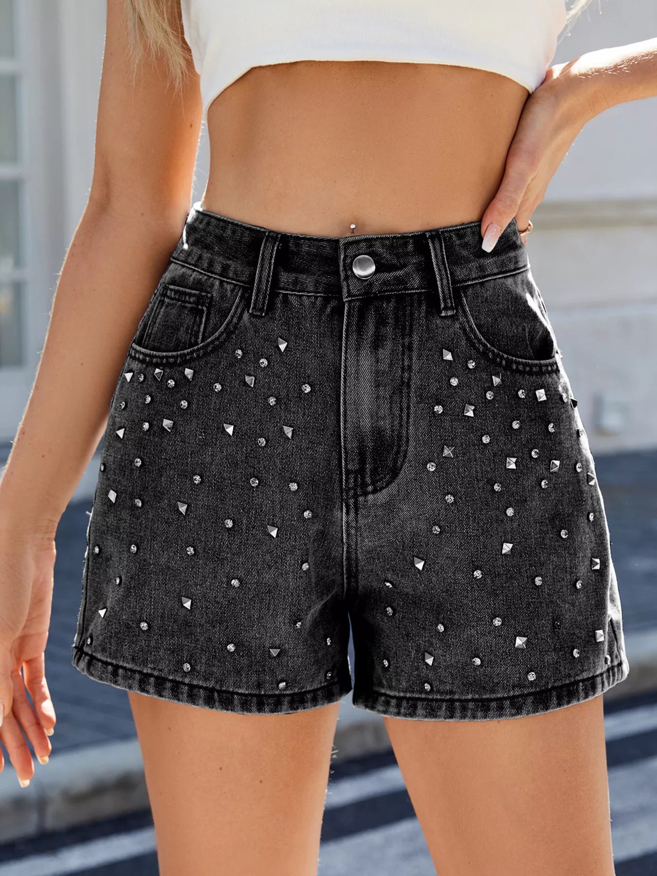 Black denim shorts with rhinestone embellishments worn by a person.
