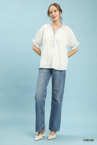 Woman wearing a white blouse and blue jeans against a light blue background