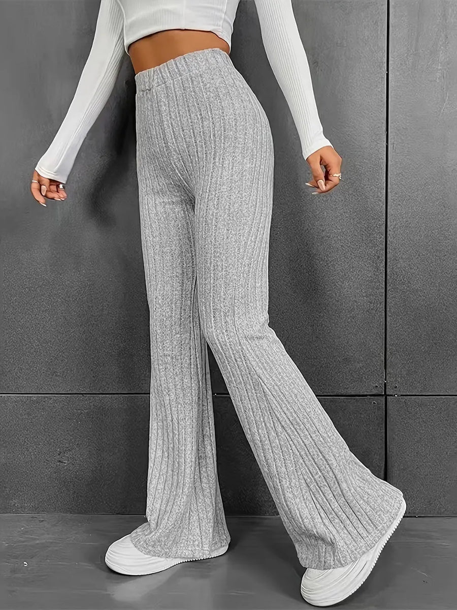 Person wearing gray ribbed knit pants and a white long-sleeve top against a gray background