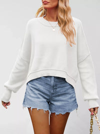 Person wearing a white oversized sweatshirt and denim shorts on a plain background