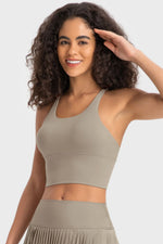 Woman wearing a beige sports bra and leggings on a plain background