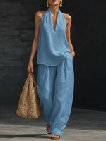 Woman in a blue outfit holding a woven bag against a dark background