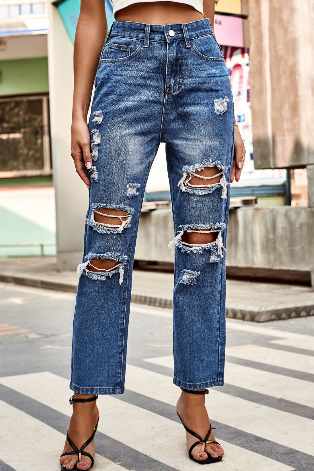 Person wearing blue ripped jeans on a city street.