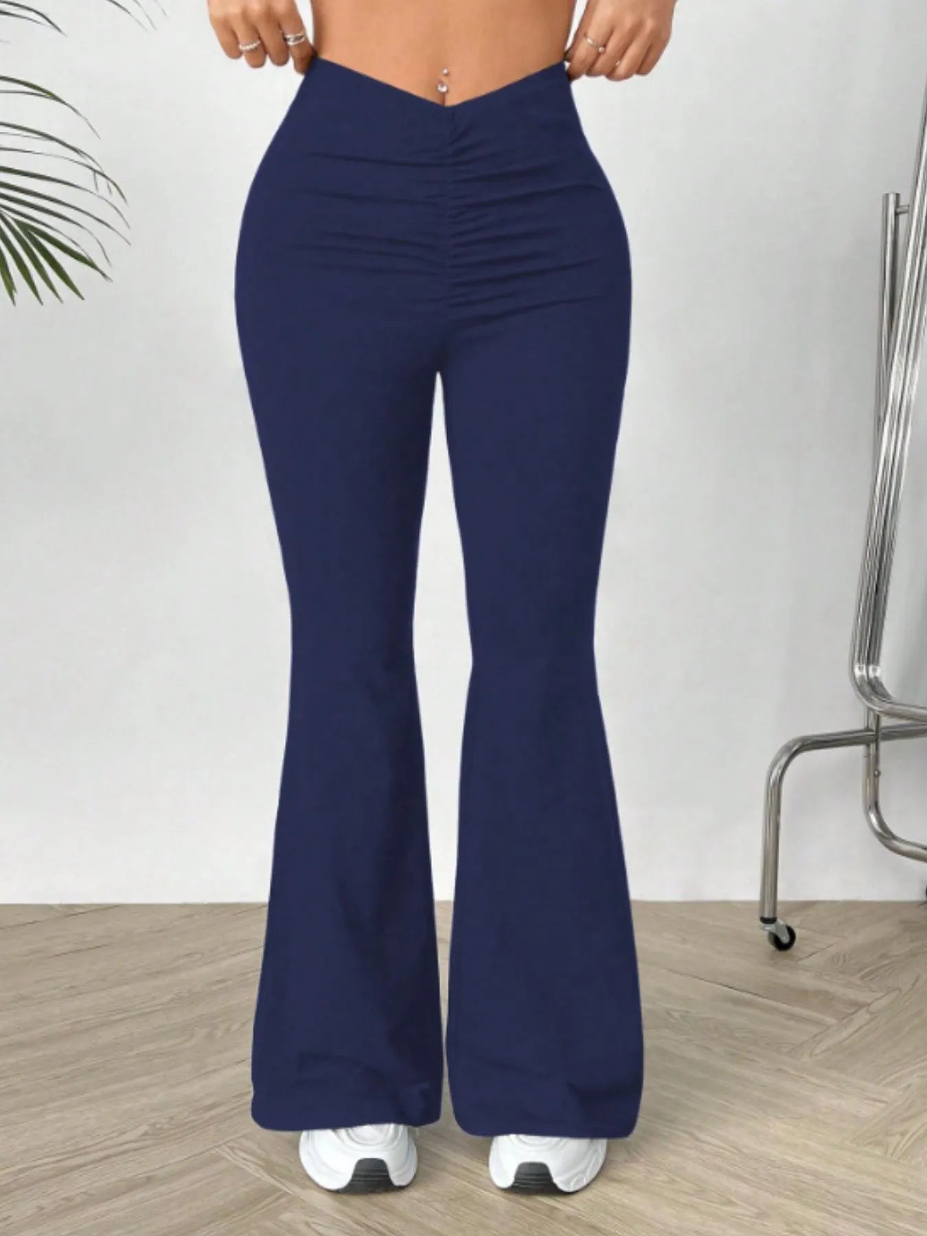 Navy blue flared pants worn by a person on a light wooden floor.