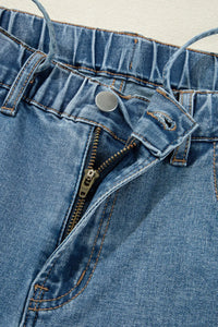 Close-up of a blue denim zipper and button on a garment.
