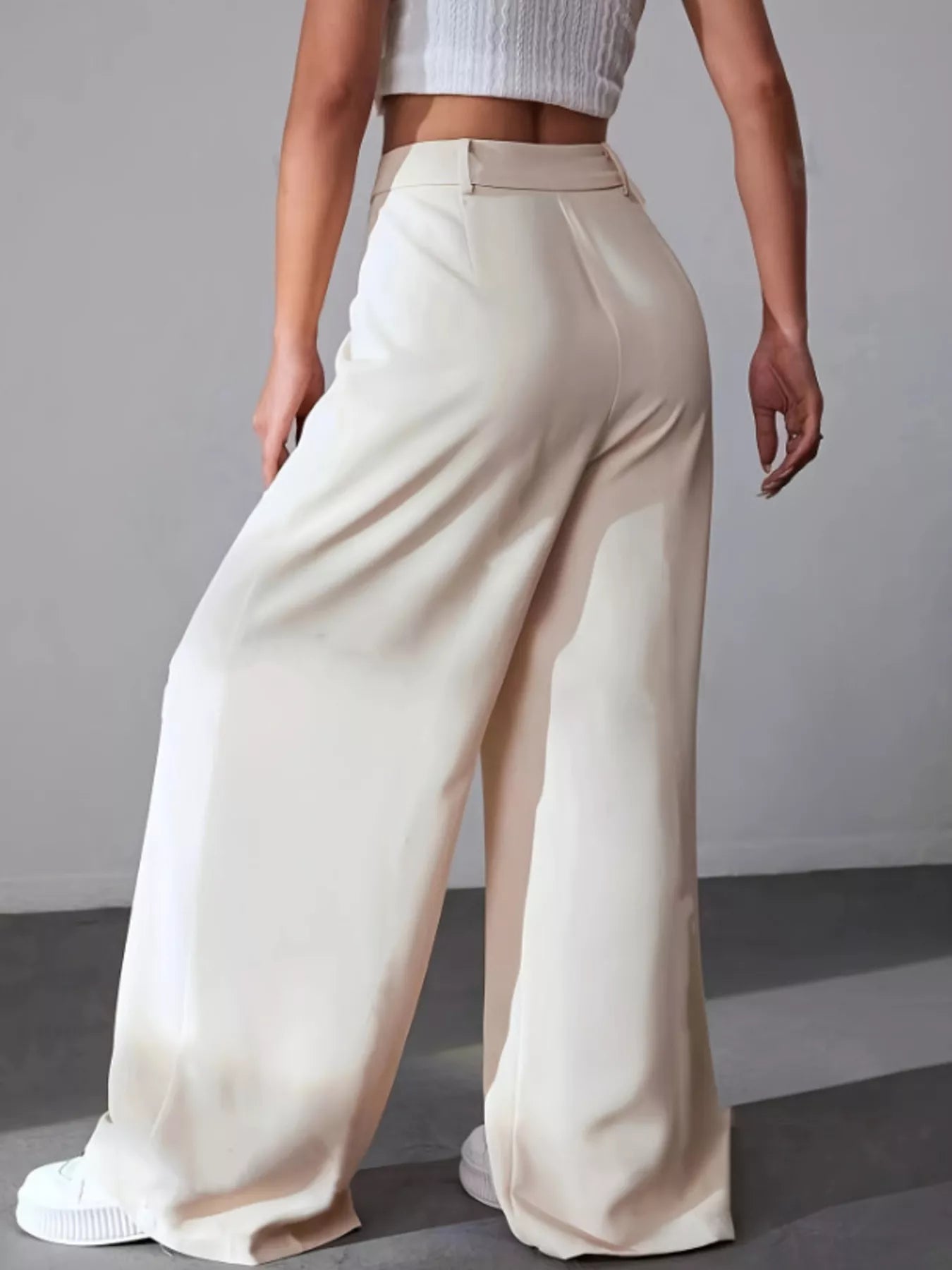 Person wearing beige wide-leg pants against a plain background