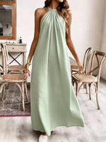 Woman wearing a light green dress in a room with wooden chairs and a mirror.
