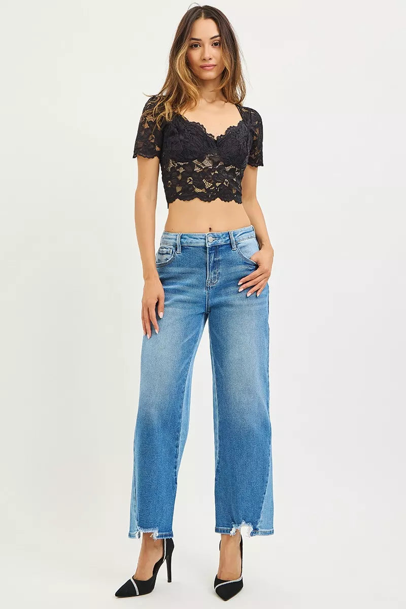 Woman wearing a black lace top and blue jeans on a white background