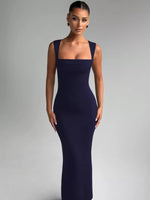 Woman wearing a dark blue evening gown against a gray background