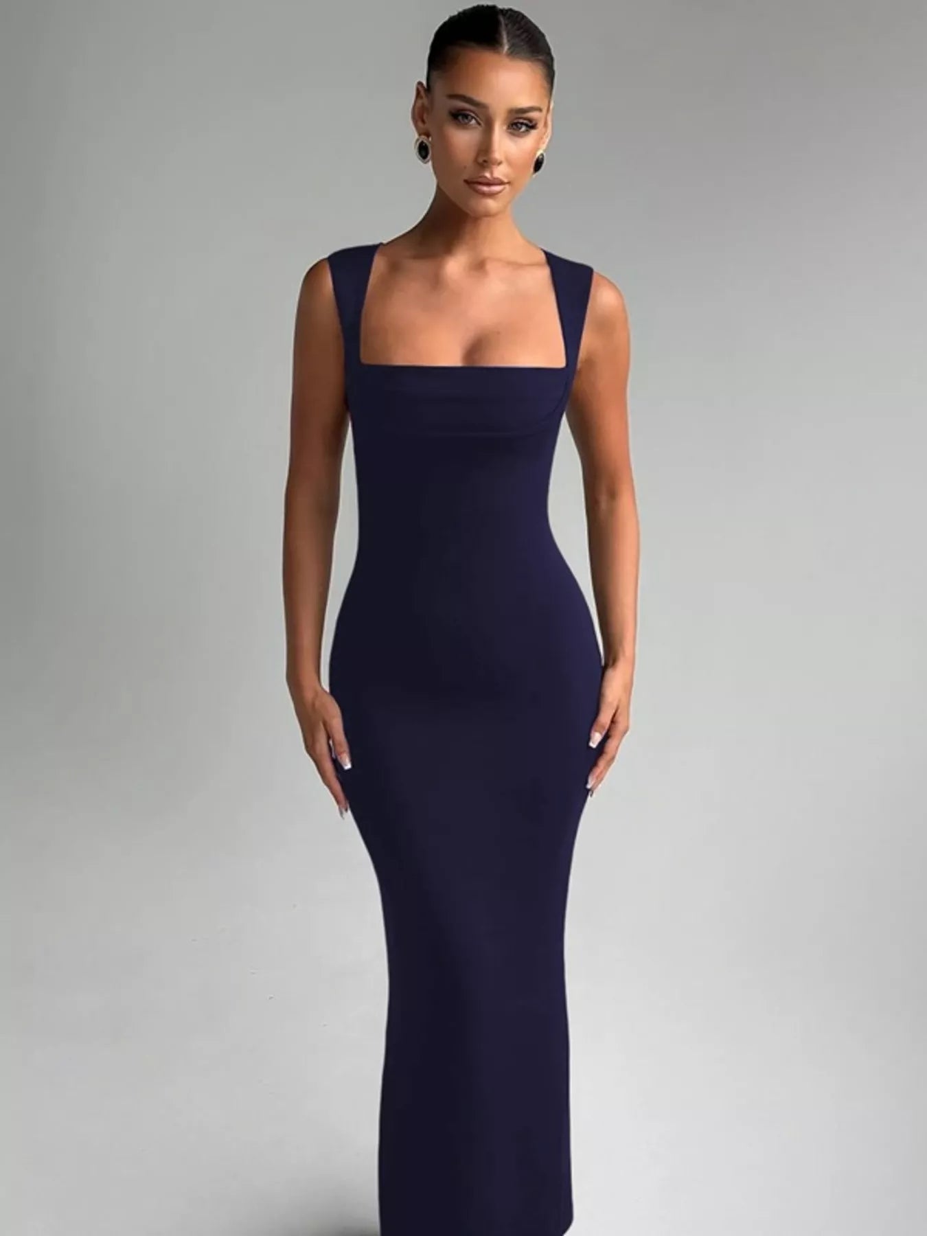 Woman wearing a dark blue evening gown against a gray background
