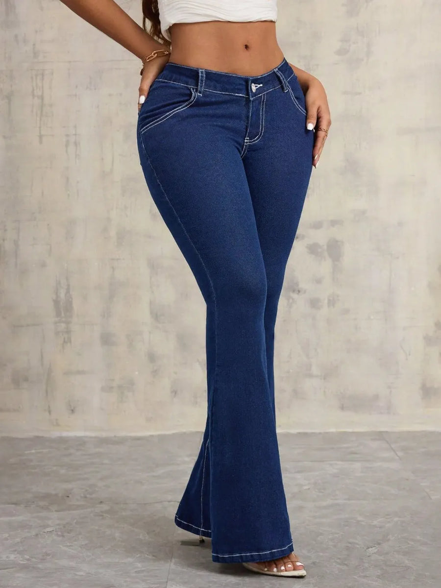 Person wearing blue flared jeans against a neutral background
