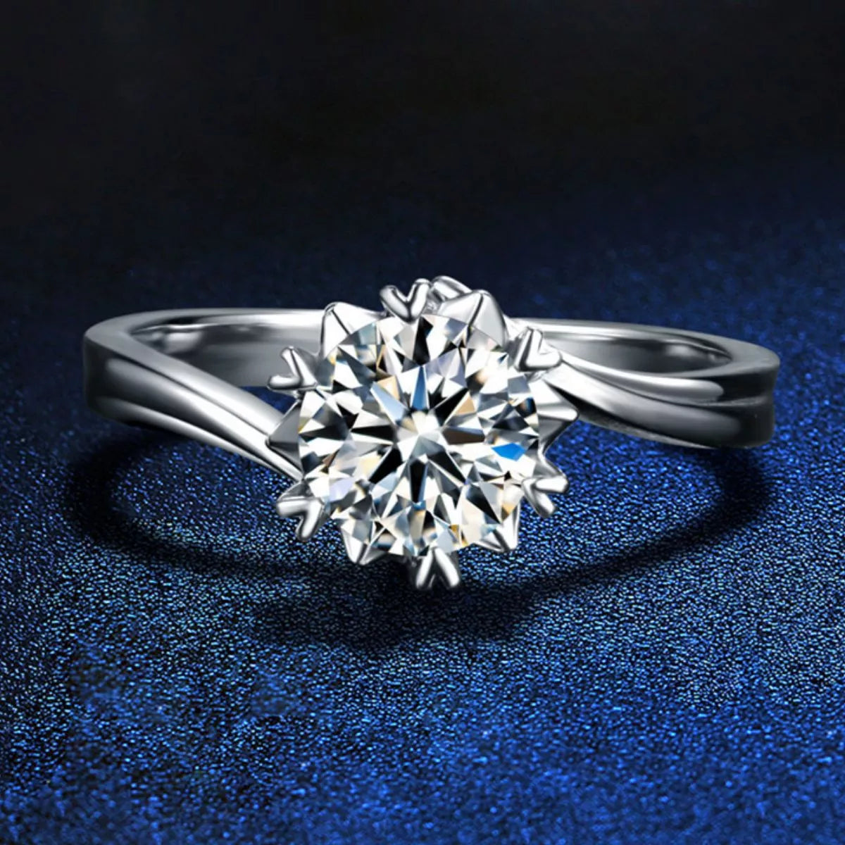 Silver ring with a large diamond on a dark blue textured background
