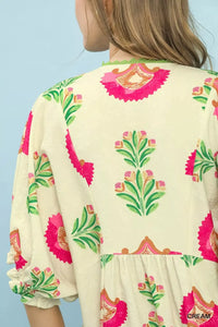 Child wearing a cream-colored outfit with pink and green floral patterns on a light blue background
