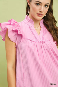 Woman wearing a pink dress with ruffled sleeves against a light green background