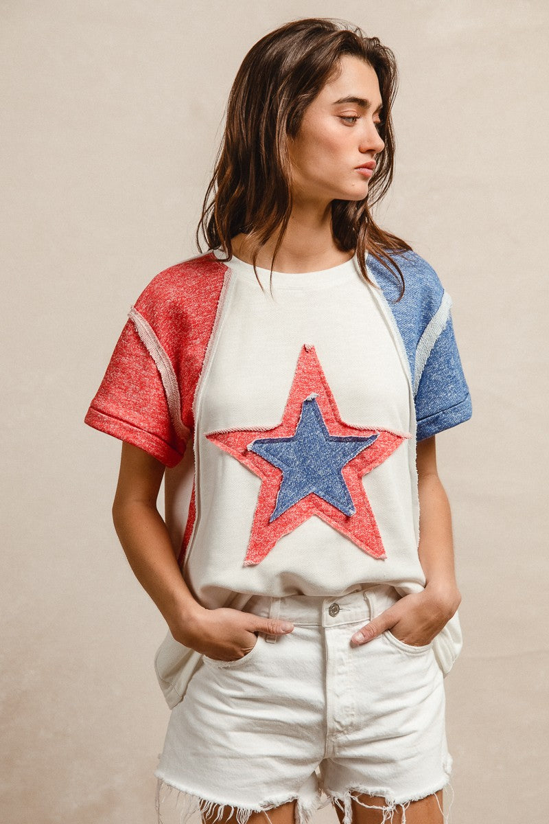Woman wearing a colorful star-themed t-shirt with red, white, and blue sleeves.