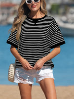 Woman wearing a black and white striped shirt and white shorts on a beach.
