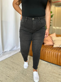 Person wearing black high-waisted jeans and a black top in a casual setting.