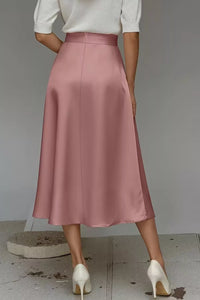 Person wearing a pink skirt and white shoes on a plain background