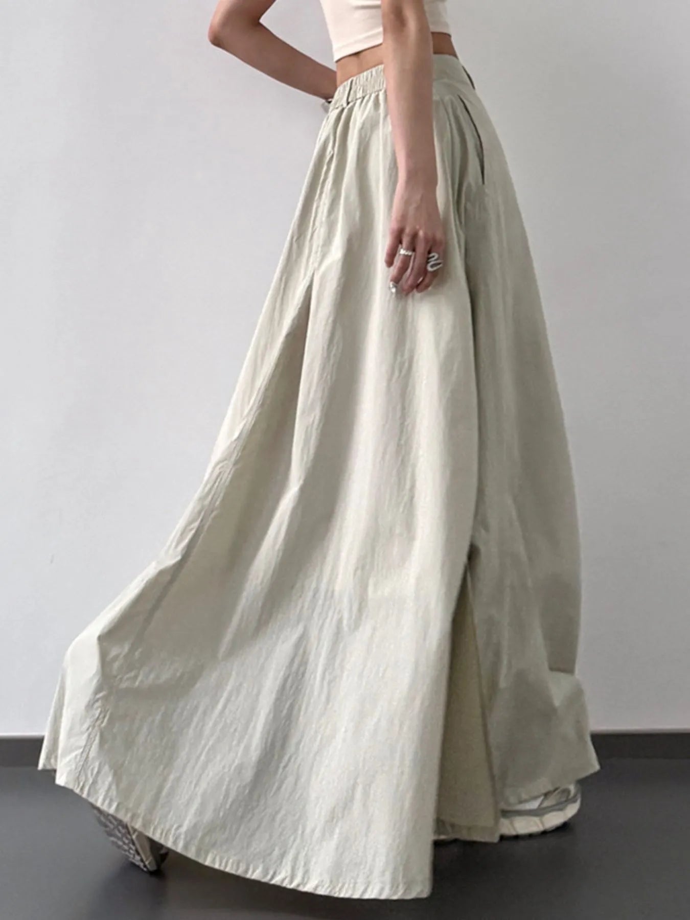 Person wearing a long beige skirt against a plain background