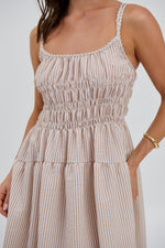 Woman wearing a beige and white striped dress on a plain background
